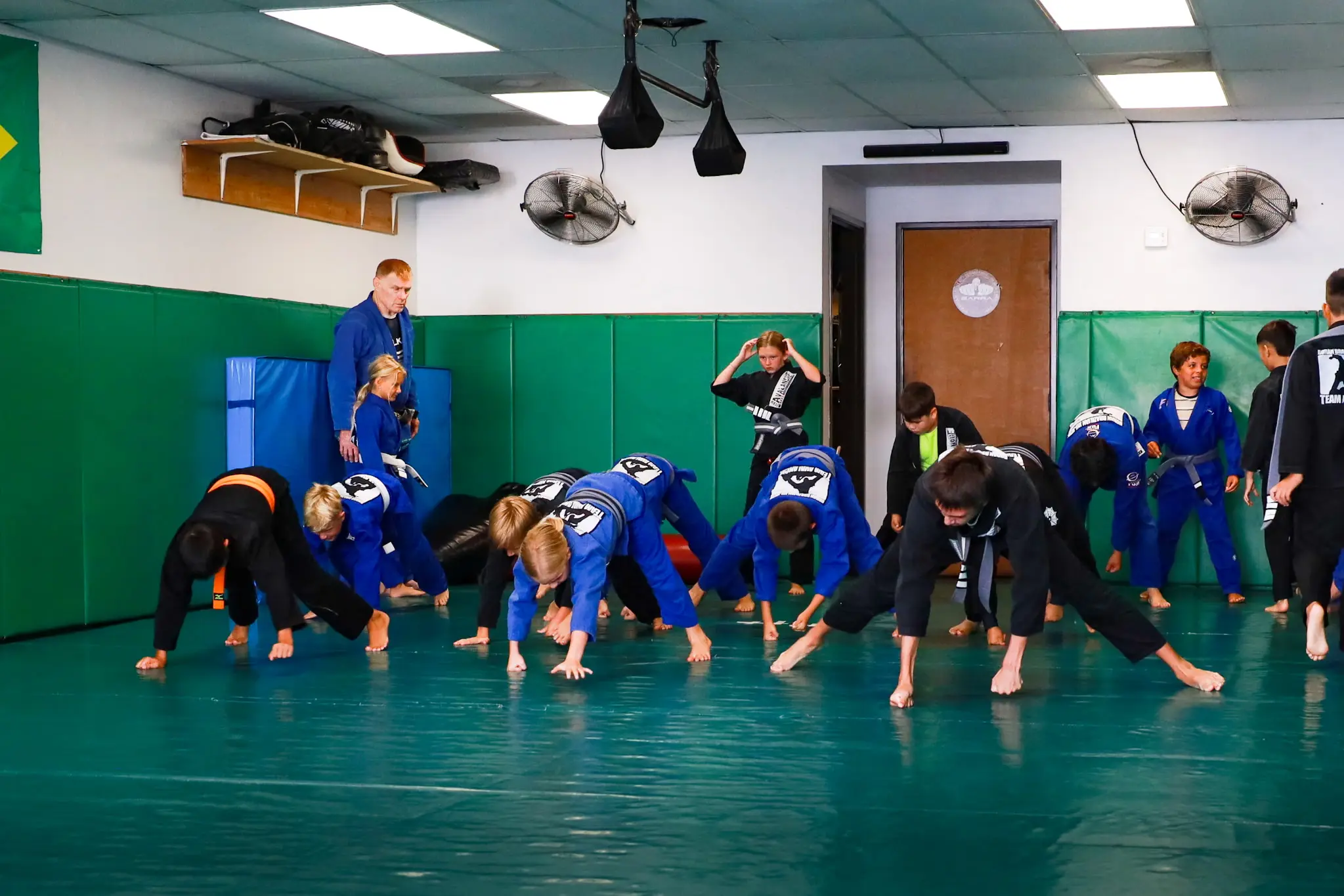 A full class of children bear-crawling the length of the mat during the warm-up at Boran Brazilian Jiu-Jitsu in Costa Mesa