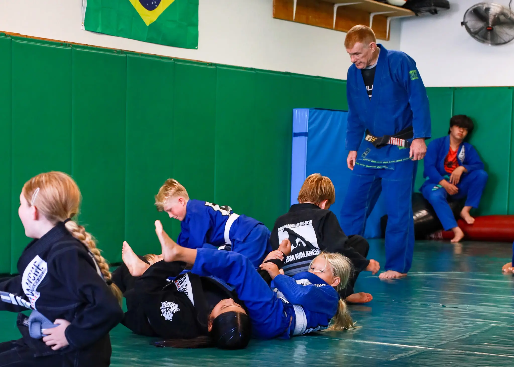 Professor James Boran standing over several pairs of students rolling during the live rounds at the end of class