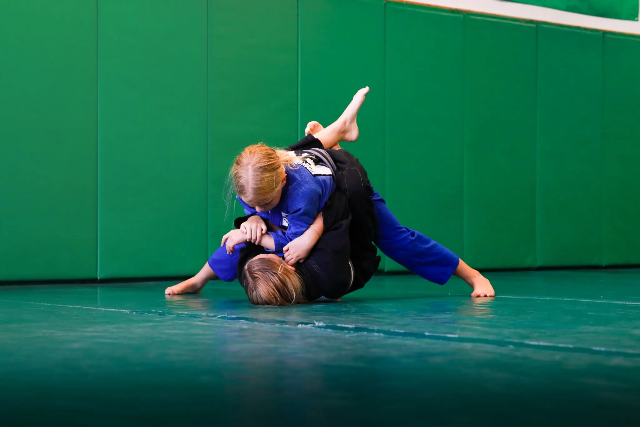 A young student pinning a partner in side control during a live round