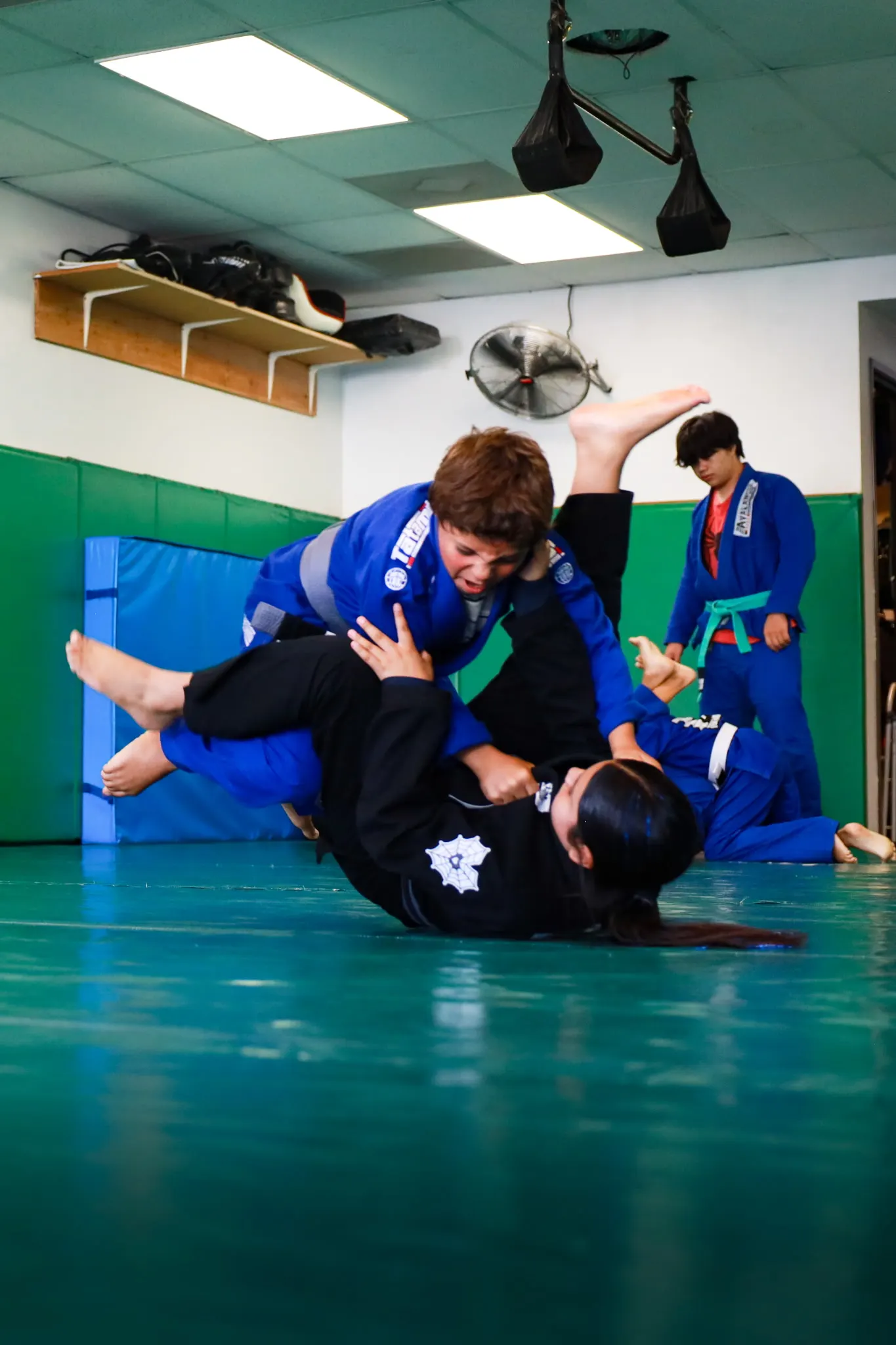 A student in a blue gi passing his partner's guard during a live round at Boran Brazilian Jiu-Jitsu